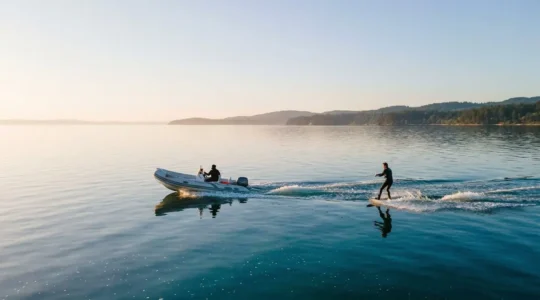Semi-rigide de petite taille tractant un wakeboarder sur un plan d'eau calme au petit matin