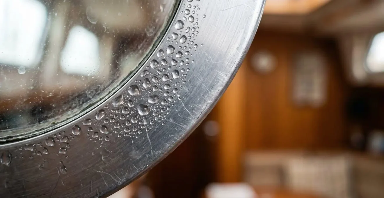 Gros plan sur la condensation formée sur un cadre de hublot en aluminium de bateau