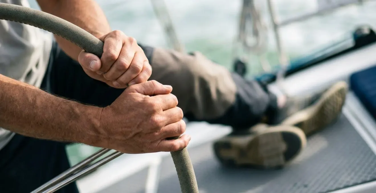 Détail des points d'appui d'un barreur à la barre d'un voilier montrant la posture tripodie